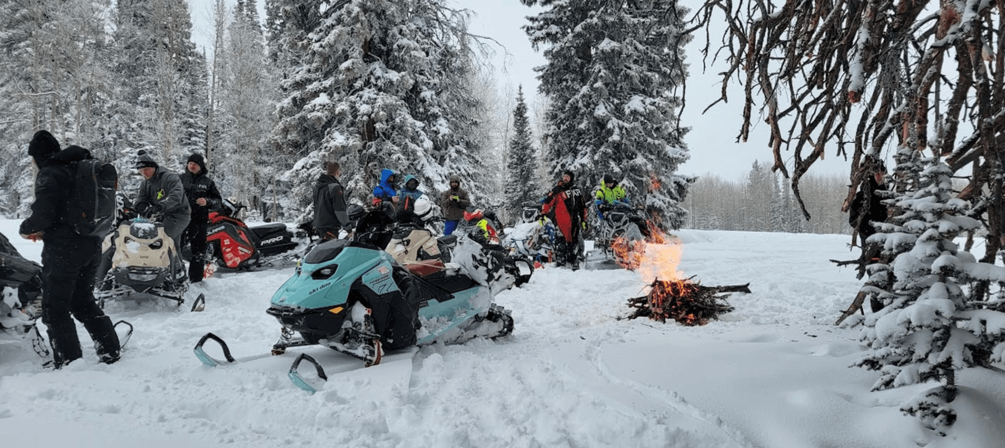 A group of veterans on their snowmobiles gathering around a campfire